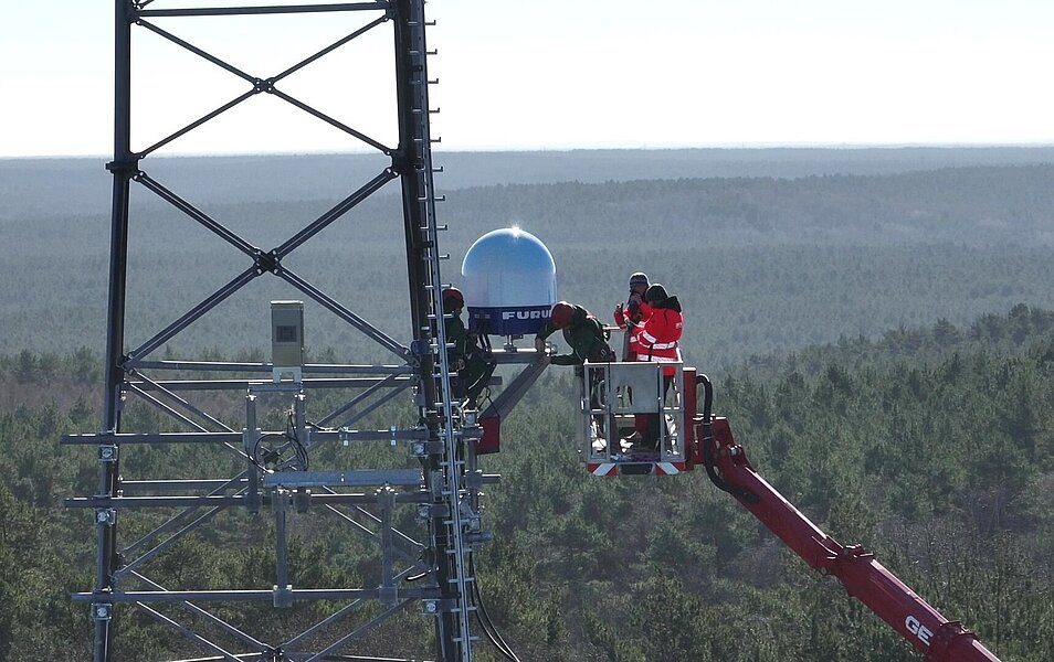 Technicians use an elevated platform to install the AgroHyd-X radar on a radio mast