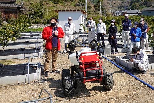 XAG R150 at a Japanese orchard roadshow. The source identifies this photograph as mandarin-orange spraying, not the separate apple-pollination trial.
