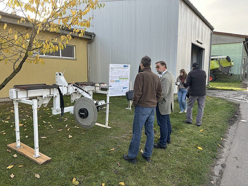 Field-day visitors discuss a soil sensor platform displayed outside a farm building