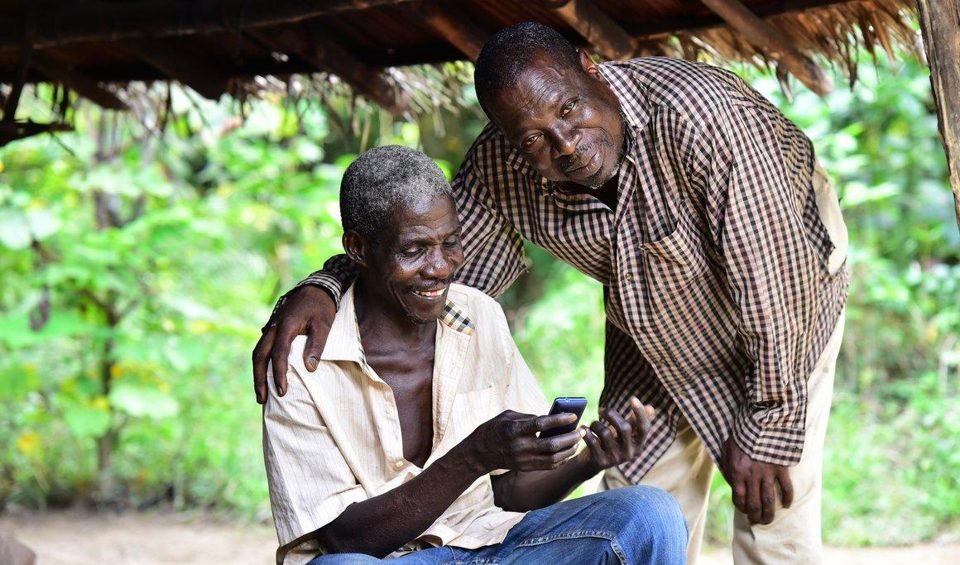 Two people looking at a mobile phone in a rural setting