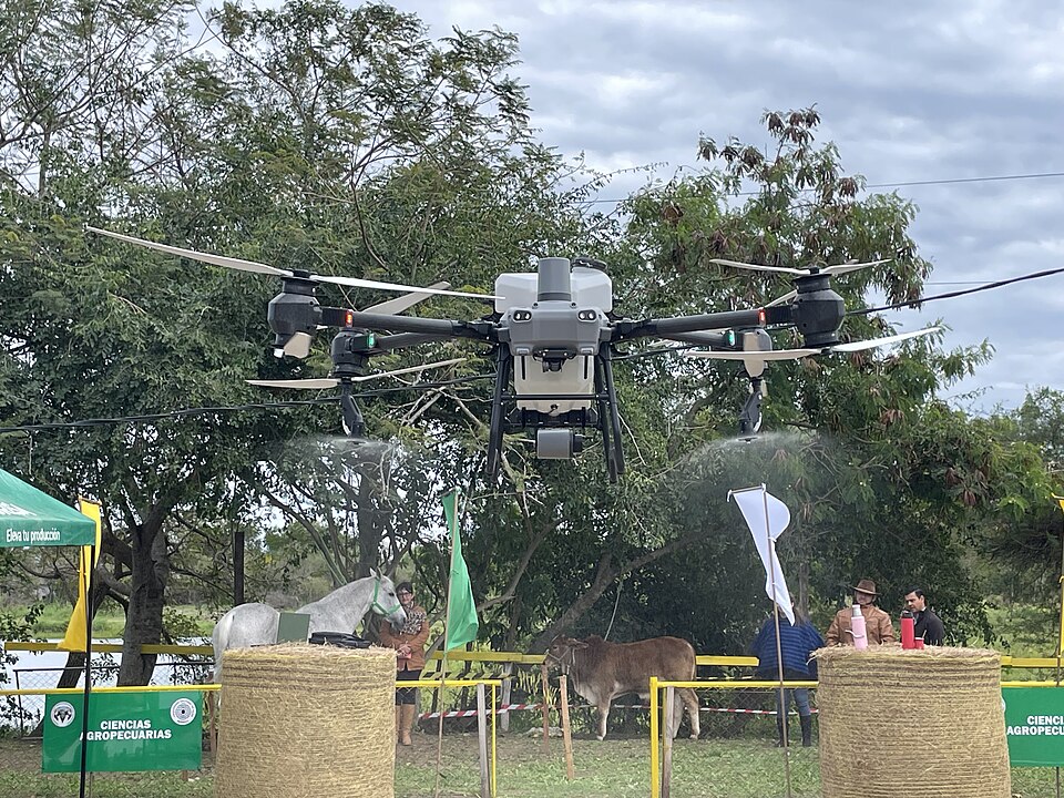 A DJI Agras T50 spraying in flight during a demonstration in Paraguay.