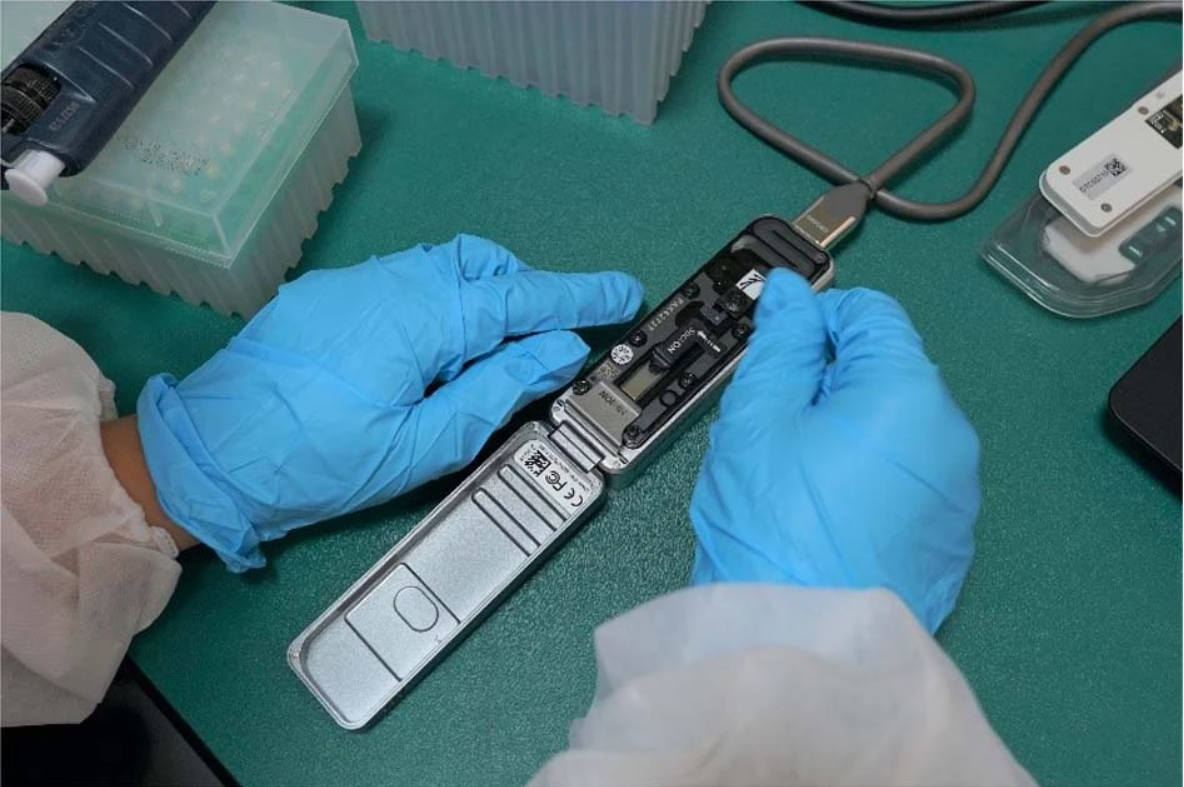 Gloved hands prepare a MinION portable DNA sequencer on a laboratory bench