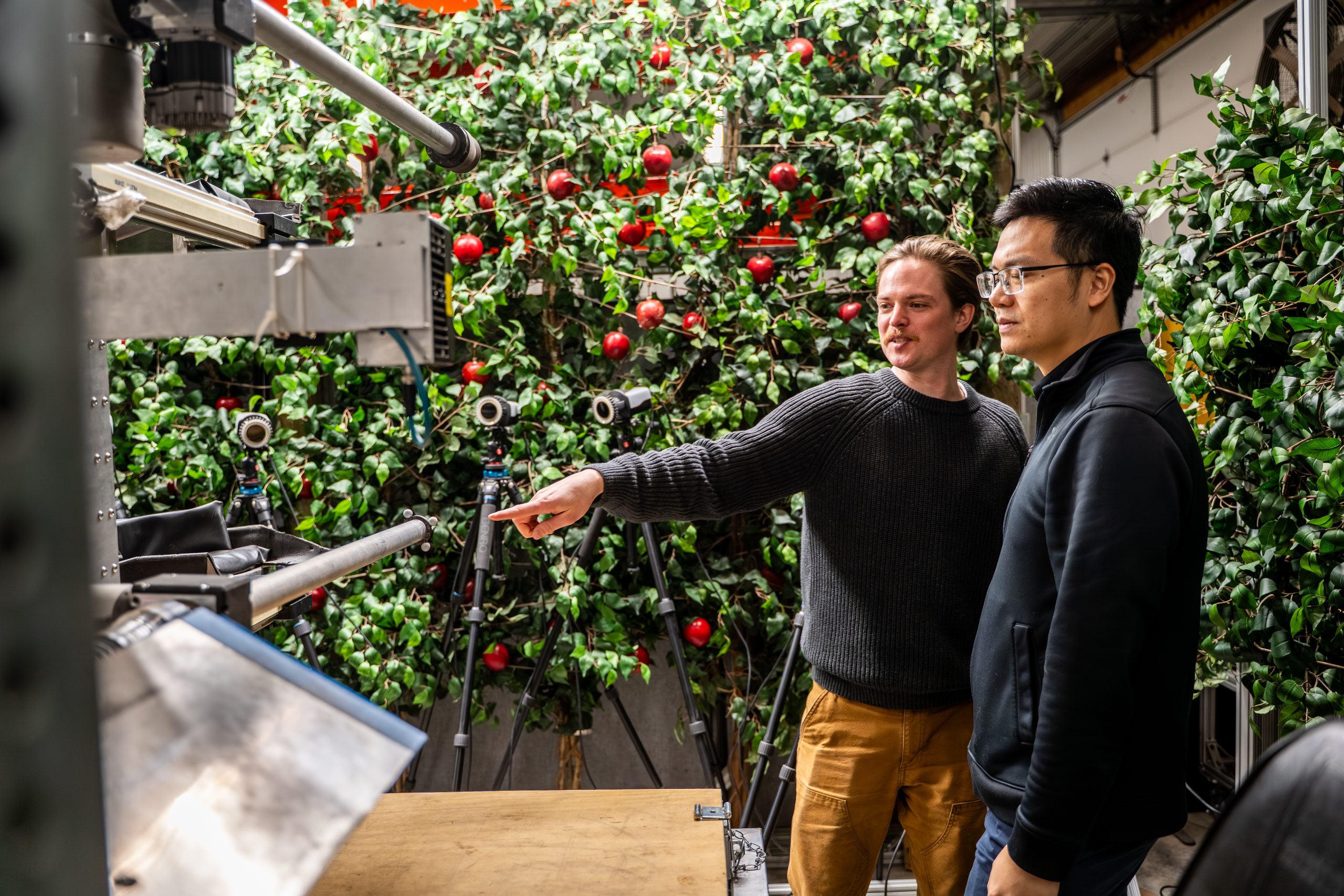 Michigan State University researchers examining components of a robotic apple harvesting system in a laboratory.