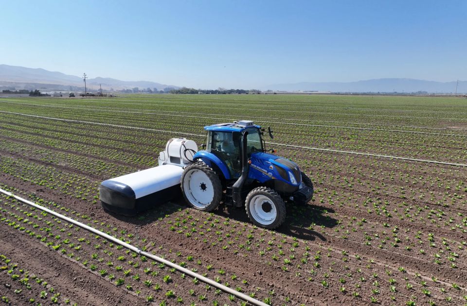A tractor pulls a Verdant precision application implement across crop beds.