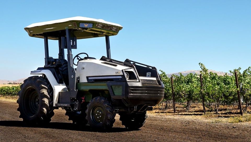A Monarch MK-V electric tractor beside vineyard rows.