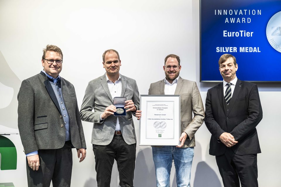 Four people at the EuroTier 2024 silver innovation award presentation, with a medal and Weidemann certificate.